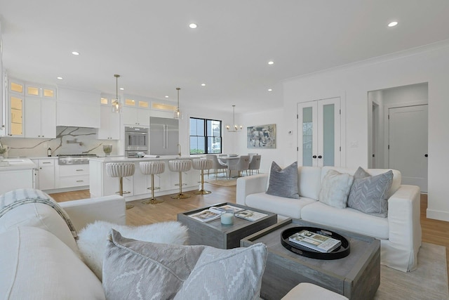 living area with french doors, ornamental molding, light wood-type flooring, and recessed lighting