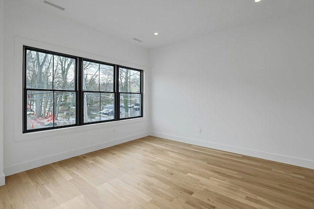 empty room featuring light wood-style floors, recessed lighting, visible vents, and baseboards