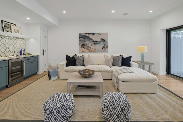 living area with a dry bar, recessed lighting, visible vents, light wood-style flooring, and beverage cooler