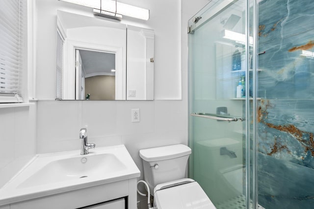 bathroom featuring tile walls, backsplash, vanity, toilet, and a shower with door