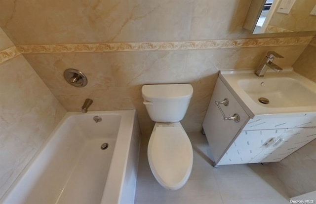 bathroom with tile patterned floors, toilet, tile walls, vanity, and a bathing tub