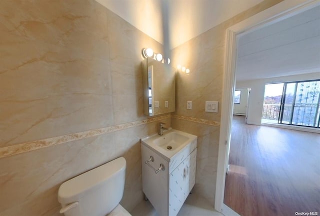 bathroom featuring vanity, toilet, and tile walls