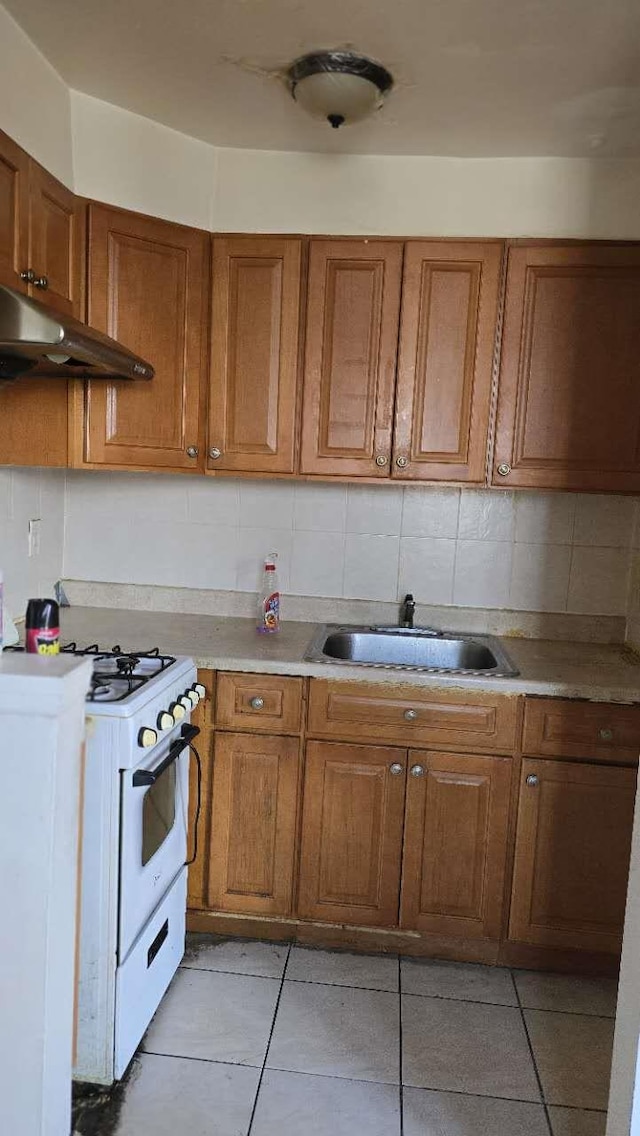 kitchen featuring white range with gas cooktop, sink, backsplash, and light tile patterned floors