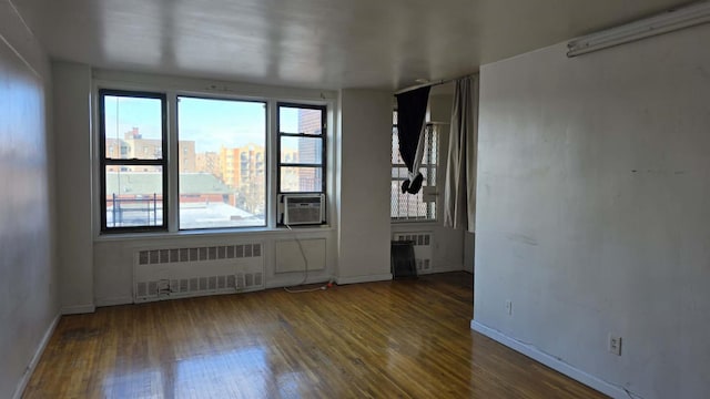 unfurnished room featuring cooling unit, dark wood-type flooring, and radiator heating unit