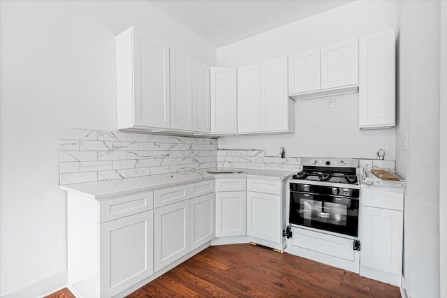 kitchen with white cabinetry, dark hardwood / wood-style floors, range with gas stovetop, light stone countertops, and decorative backsplash