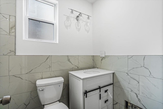 bathroom with vanity, tile walls, and toilet