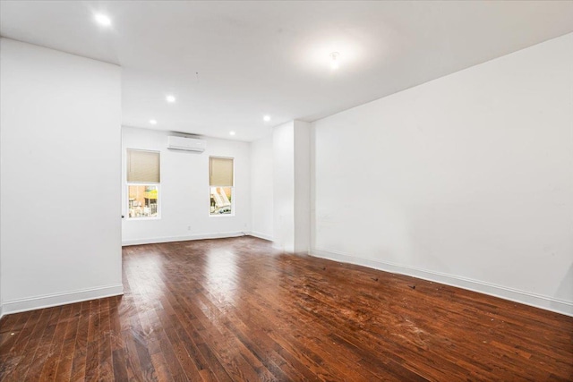 unfurnished room with an AC wall unit and dark hardwood / wood-style flooring