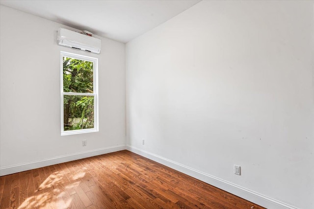 unfurnished room with wood-type flooring and an AC wall unit