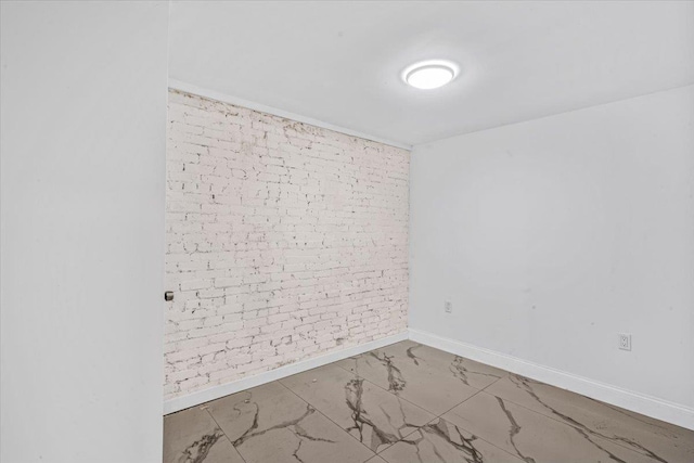 unfurnished room featuring brick wall