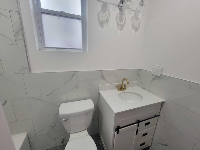 bathroom featuring vanity, tile walls, and toilet