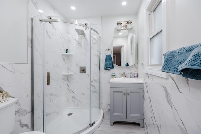 bathroom with vanity, toilet, tile walls, and a shower with shower door