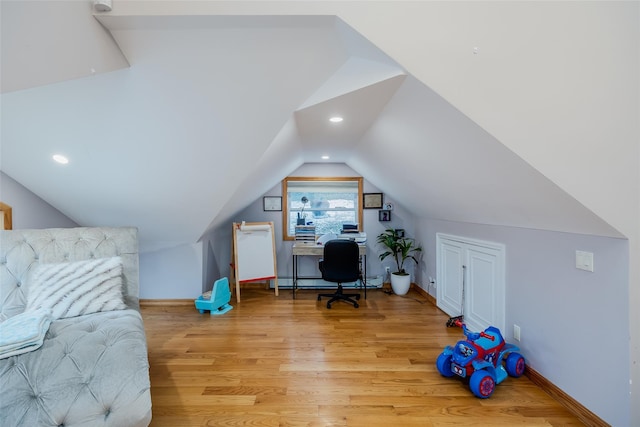 home office with vaulted ceiling, a baseboard radiator, and light wood-type flooring