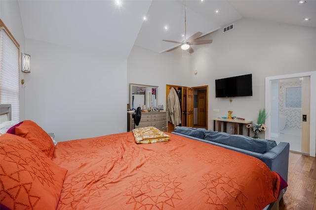 bedroom featuring hardwood / wood-style floors, high vaulted ceiling, and ensuite bath