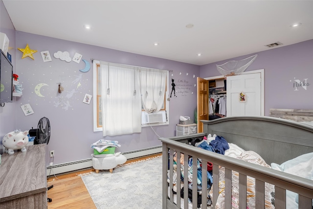 bedroom featuring light hardwood / wood-style flooring, cooling unit, and a baseboard radiator