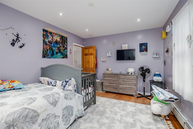 bedroom with a baseboard radiator and light hardwood / wood-style floors