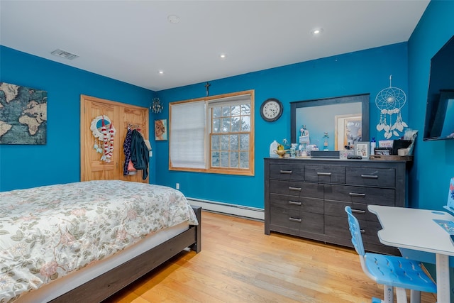 bedroom featuring a baseboard heating unit, a closet, and light wood-type flooring