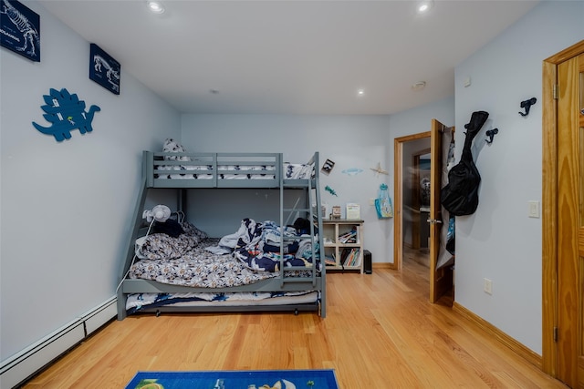 bedroom featuring wood-type flooring and a baseboard heating unit