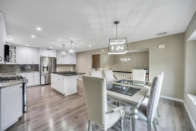 dining area with light hardwood / wood-style floors and a notable chandelier