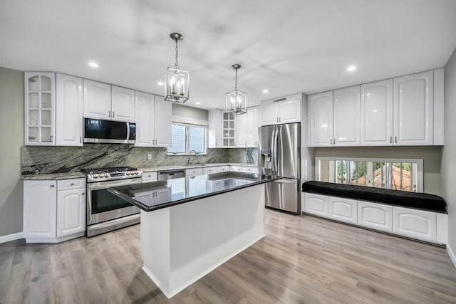 kitchen featuring white cabinetry, sink, hanging light fixtures, stainless steel appliances, and light hardwood / wood-style flooring