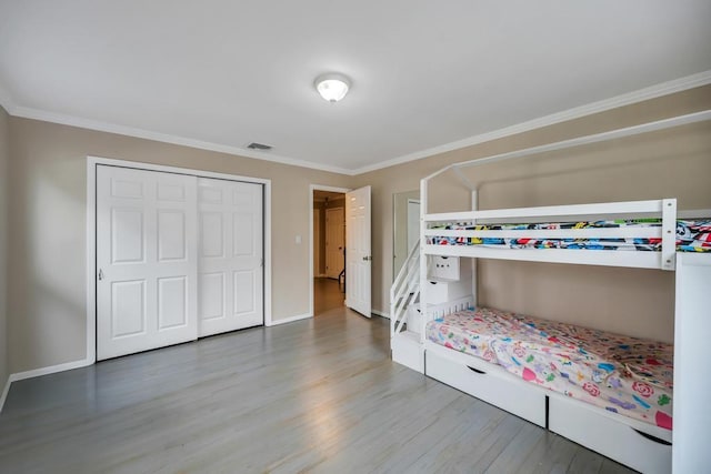 bedroom with ornamental molding, wood-type flooring, and a closet