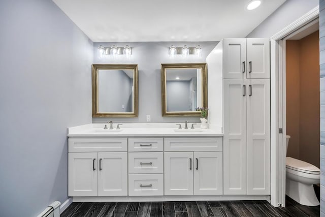 bathroom featuring vanity, a baseboard heating unit, and toilet