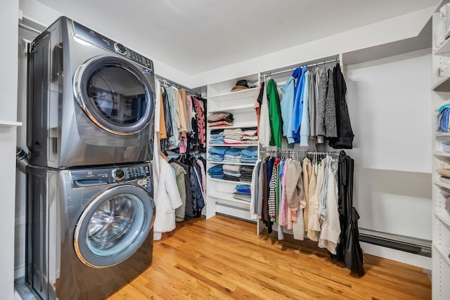 laundry area with wood-type flooring and stacked washing maching and dryer