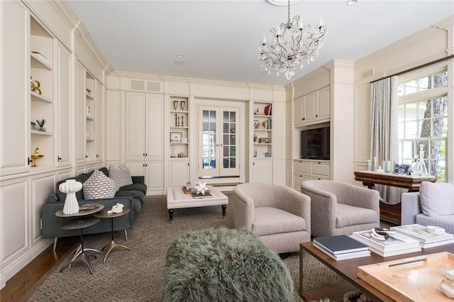 living room featuring french doors, an inviting chandelier, ornamental molding, dark hardwood / wood-style flooring, and built in features