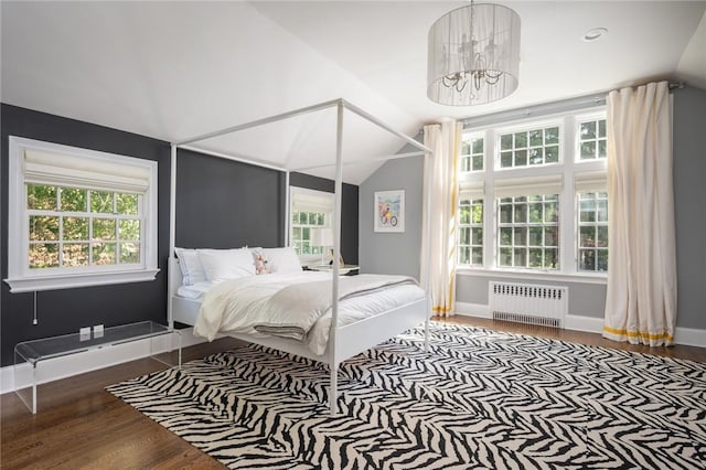 bedroom with lofted ceiling, radiator heating unit, dark hardwood / wood-style flooring, and multiple windows