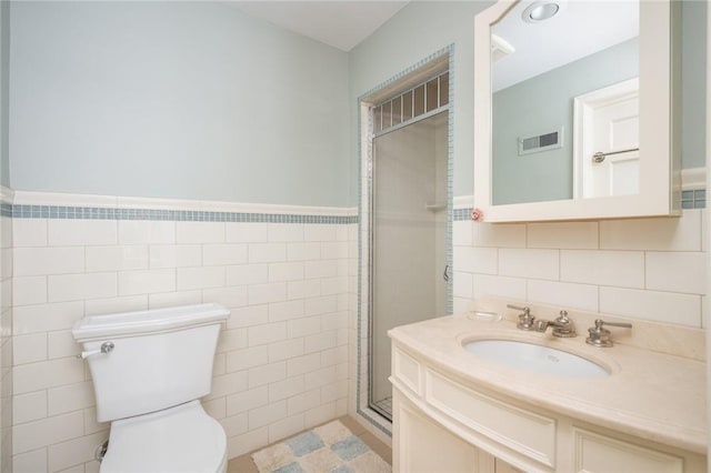 bathroom with vanity, a shower with shower door, tile walls, and toilet