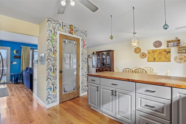 kitchen with ceiling fan, light hardwood / wood-style floors, butcher block countertops, and hanging light fixtures