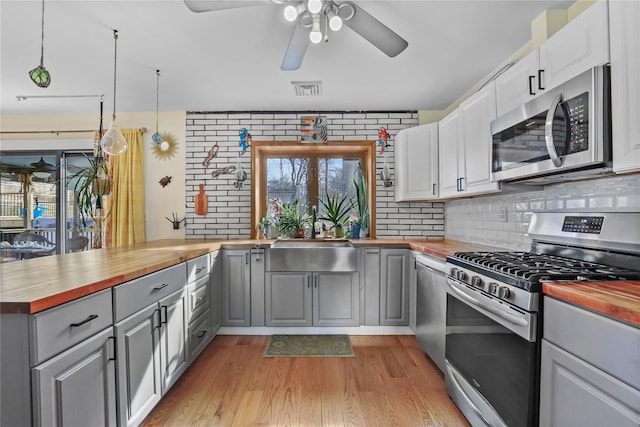 kitchen featuring sink, butcher block counters, gray cabinetry, stainless steel appliances, and white cabinets