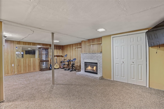 basement with a brick fireplace, carpet flooring, a textured ceiling, and wood walls