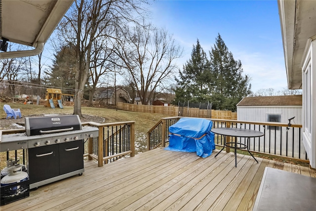 deck with grilling area, an outdoor structure, and a playground