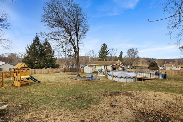 view of yard with a playground, a covered pool, and a storage unit