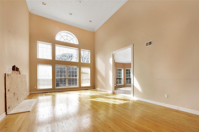 unfurnished living room featuring ornamental molding, light hardwood / wood-style floors, and a high ceiling