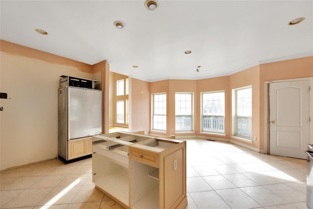 kitchen with light tile patterned floors, ornamental molding, a center island, and a healthy amount of sunlight