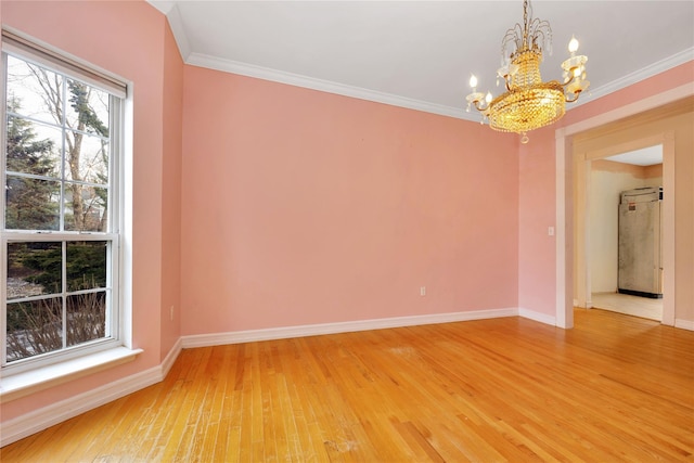 unfurnished room featuring an inviting chandelier, ornamental molding, and hardwood / wood-style floors