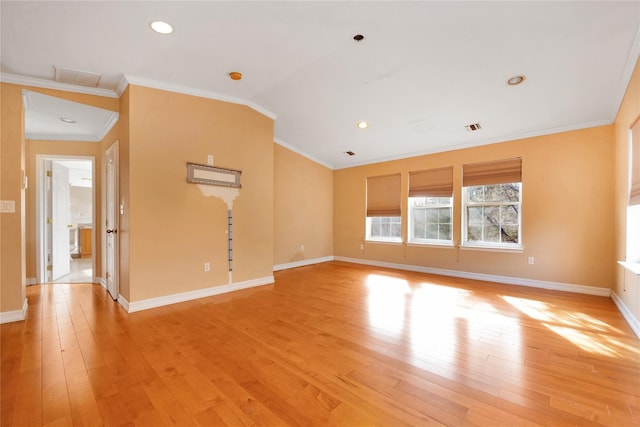 empty room featuring vaulted ceiling, ornamental molding, and light hardwood / wood-style flooring