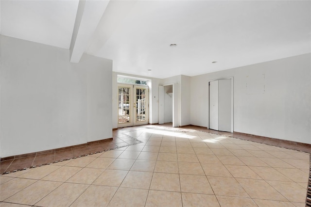 empty room with french doors, beamed ceiling, and light tile patterned floors