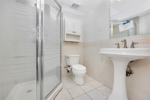 bathroom with tile walls, tile patterned floors, toilet, and walk in shower