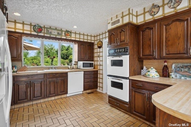 kitchen with white appliances, sink, and a textured ceiling