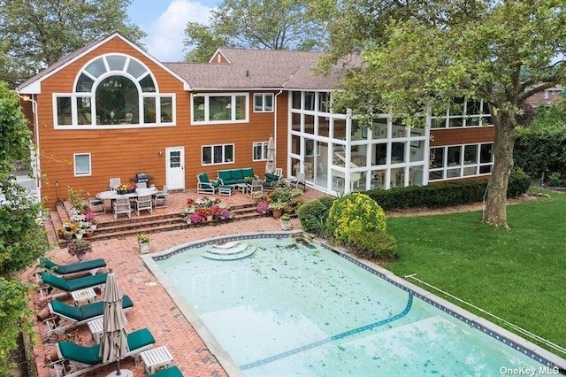 rear view of property featuring a yard, a sunroom, and a patio