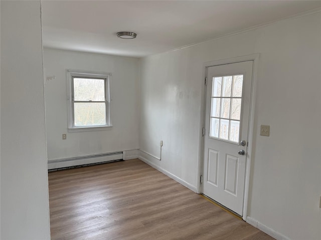 interior space featuring a baseboard radiator, a wealth of natural light, and light hardwood / wood-style floors