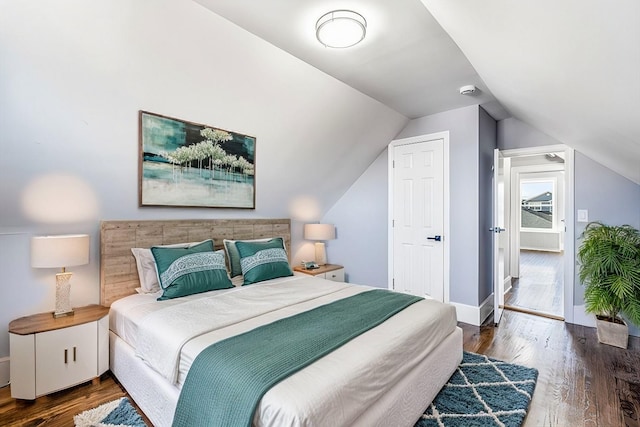 bedroom with dark wood-type flooring and lofted ceiling