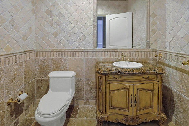 bathroom with vanity, toilet, and tile walls