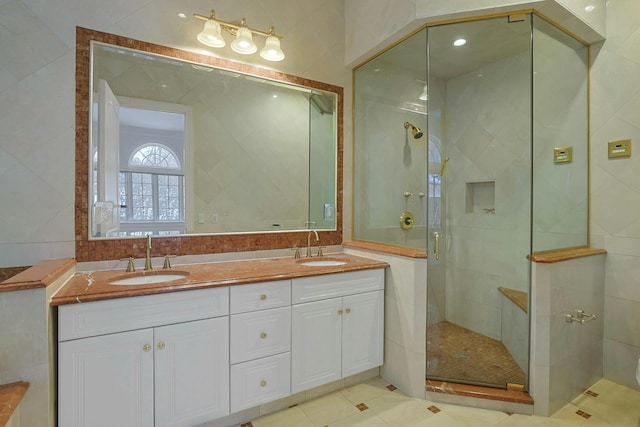 bathroom with vanity, a shower with shower door, and tile walls