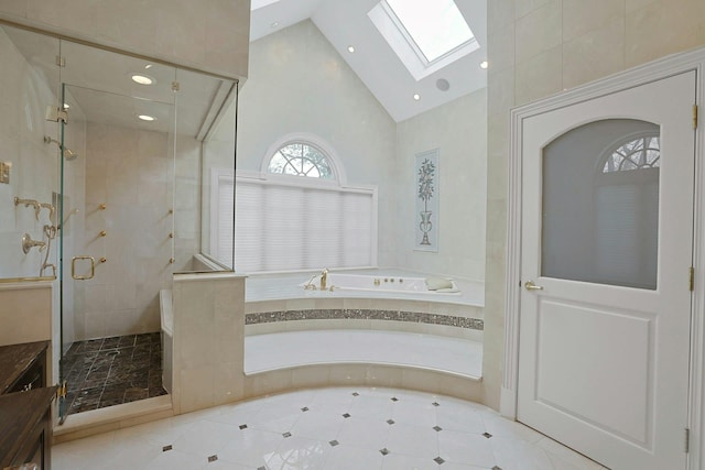 bathroom featuring shower with separate bathtub, a skylight, and high vaulted ceiling