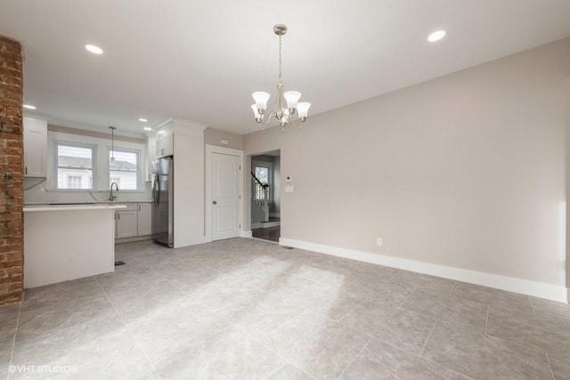 unfurnished room featuring sink and a chandelier