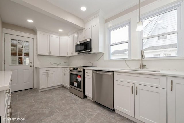 kitchen featuring white cabinetry, sink, pendant lighting, and stainless steel appliances