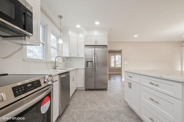 kitchen featuring sink, white cabinets, hanging light fixtures, light stone counters, and stainless steel appliances